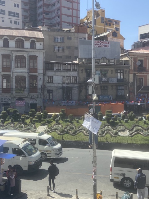 Das Bild zeigt eine Puppe, die auf einem Laternenmast aufgehanden wurde. Sie trägt ein Schild, das bspw. Diebe vor den Konsequenzen warnt, die die erhängte Puppe darstellt. Selbstjustiz ist ein weiten Teilen der Bevölkerung in und um La Paz ein ernstes Problem